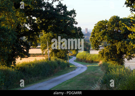 Early morning view along a winding country lane looking towards St. Mary`s Church, Warwick, Warwickshire, UK Stock Photo